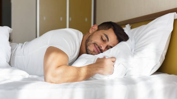 istock Young man peacefully sleeping in his bed 1182412763