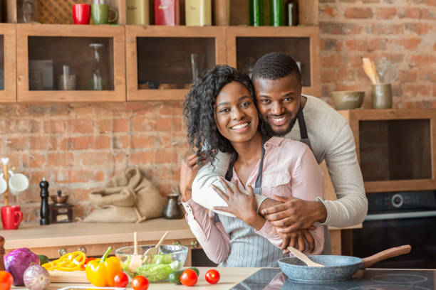 istock Cheerful black man hugging his wife while cooking at kitchen 1182413112