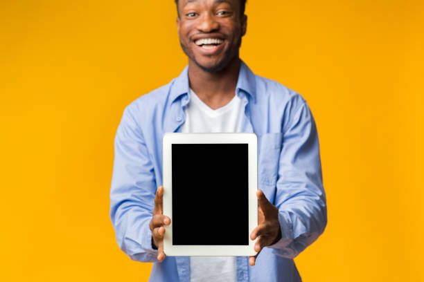 istock Black Guy Showing Blank Tablet Screen On Yellow Background, Mockup 1182413127