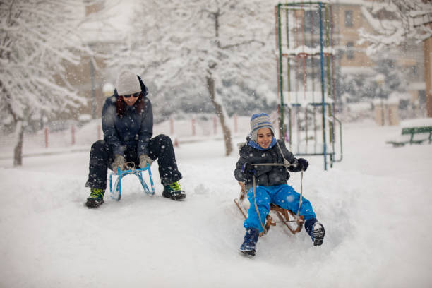 istock Mother and son sledding together 1182415818