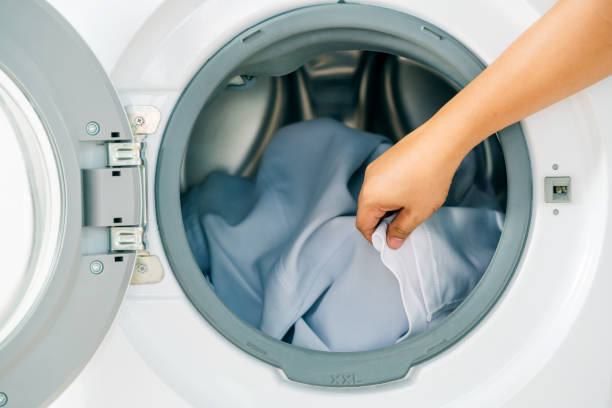 istock Close up man loading clothes into washing machine. Laundry concept. 1182419415