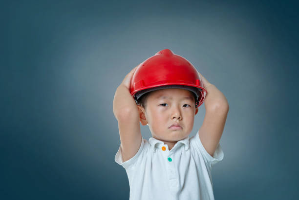Little boy engineer with protective helmet against dark blue background.