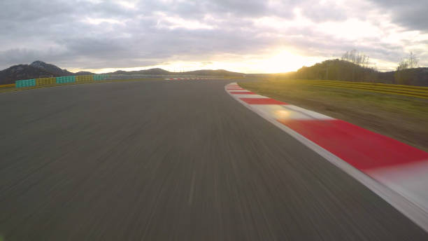 istock POV: Racing a car down the empty asphalt circuit on a beautiful golden evening. 1182421086