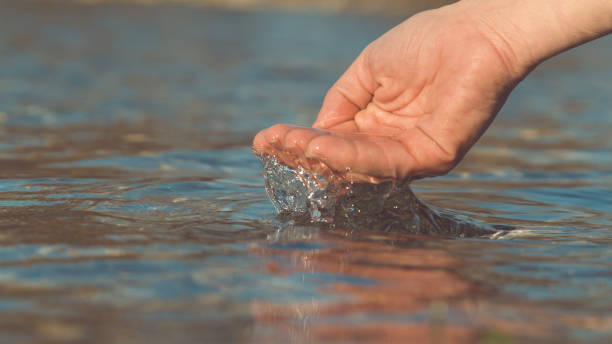 istock MACRO, DOF: Unknown young woman scoops up the glassy water from a pure river. 1182421107