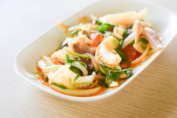 istock Stir fried squid with salted egg yolk on white dish on table background. thai food. 1182421767
