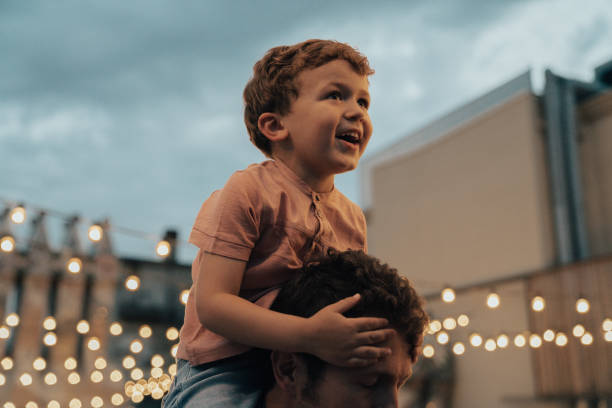 Boy at a party with lights on background Boy at a party with lights on background on shoulders stock pictures, royalty-free photos & images