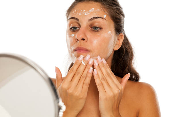 istock young woman applying cream to her face 1182422051