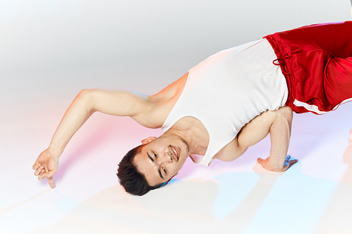 Isolated Korean breakdancer training on white background, performing Air Chair element of downrock breakdance.