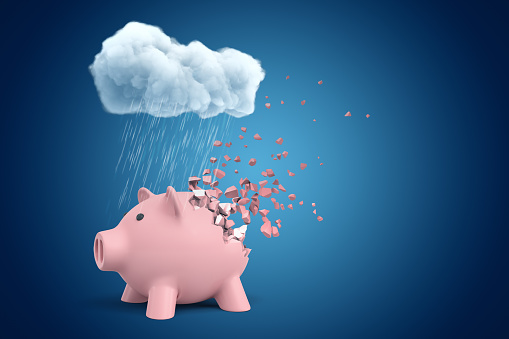 3d rendering of pink piggy bank that is dissolving in pieces, standing under cloud of pouring rain on blue copyspace background. Money and finance. Lose money. Go bankrupt.