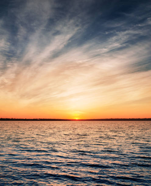 istock orange sunset in low dramatic clouds over dark water 1182423242