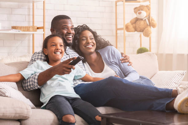 feliz familia negra relajarse y ver la televisión en casa - photography looking three people mother fotografías e imágenes de stock