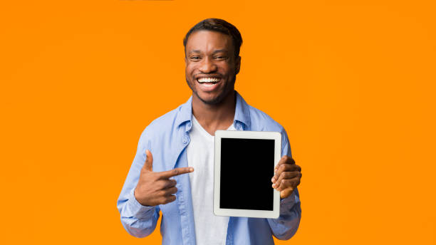 istock Black Guy Pointing Finger At Empty Tablet Screen, Orange Background 1182425526