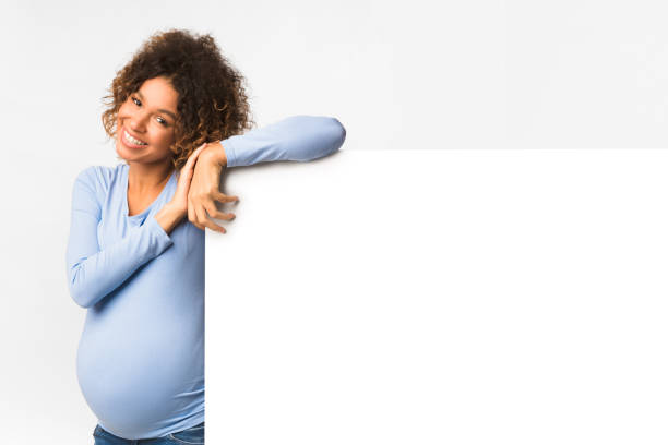 istock Happy black pregnant woman with billboard, light background 1182425549