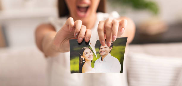 Unrecognizable Girl Tearing Apart Photo Of Happy Couple Indoor, Cropped Divorce Concept. Unrecognizable Furious Girl Tearing Apart Photo Of Happy Couple Indoor. Selective Focus, Panorama, Cropped former photos stock pictures, royalty-free photos & images