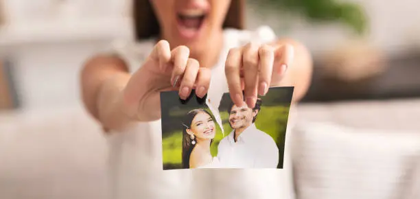 Divorce Concept. Unrecognizable Furious Girl Tearing Apart Photo Of Happy Couple Indoor. Selective Focus, Panorama, Cropped