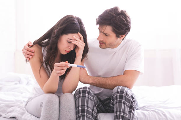 hombre molesto consolando a su esposa deprimida con prueba de embarazo negativa - árido fotografías e imágenes de stock