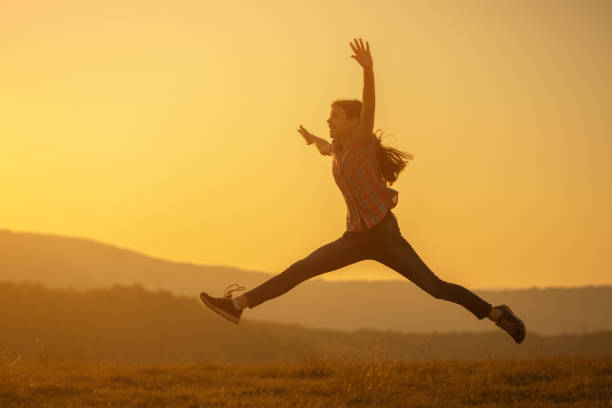 istock Happy child jumping in nature in sunset. 1182426628