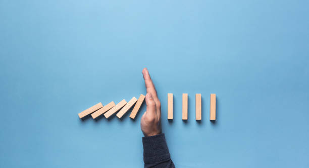 chain reaction in business concept, businessman intervening chain dominoes toppling - boundary imagens e fotografias de stock