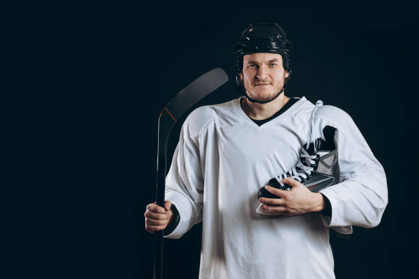 istock Handsome hockey player. Smiling at camera isolated on black background. 1182427584