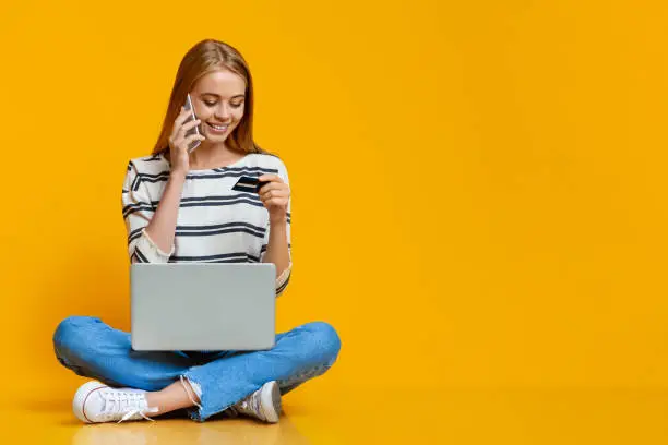 Photo of Young girl purchasing goods online with laptop and credit card