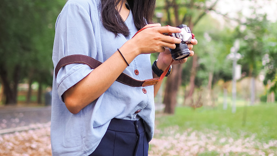 Young woman with camera outdoors,Woman's hands holding an camera at nature background.