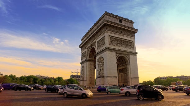 Low angle view of traffic at Arc de Triomph circle at sunset. This historical monument overlooks the avenue des champs lyses in the heart of French capital. stock photo