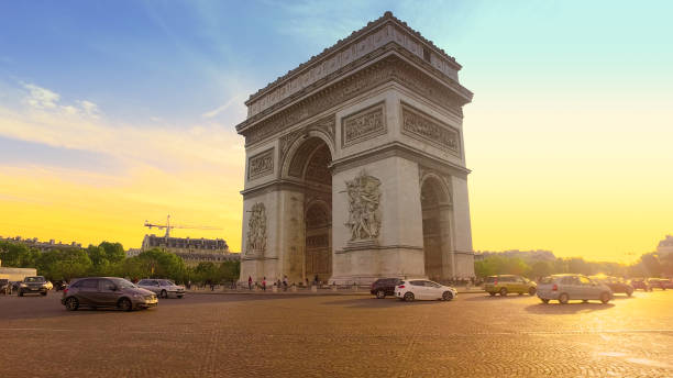 пробка на круге у триумфальной арки на закате. это один из самых известных памятников в париже, в центре парижа шарля де голля - paris france night charles de gaulle arc de triomphe стоковые фото и изображения