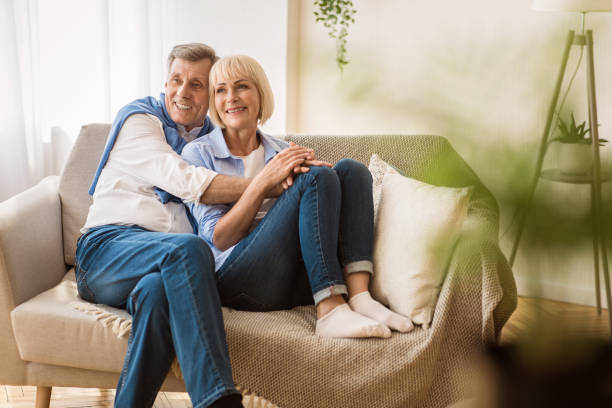 istock Romantic senior couple sitting close together on sofa 1182432038