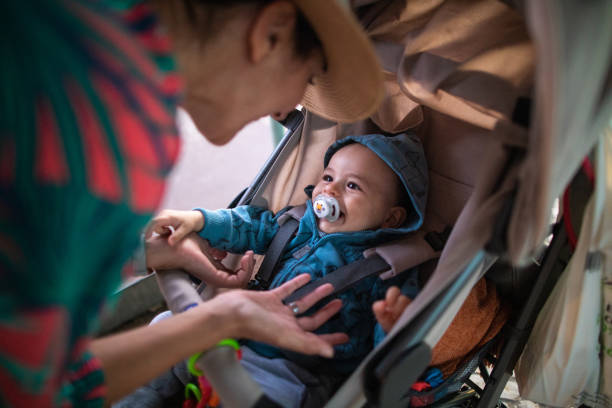 Happy cute baby in a stroller looking out and laughing in the autumn park