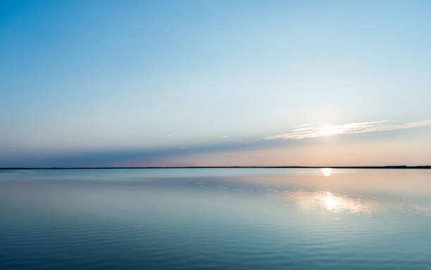 réflexions du coucher du soleil avec le paysage nuageux dans l'eau de lac - motif en vagues photos photos et images de collection