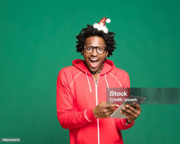 Funny Christmas Portrait Of Excited Young Man Wearing In Red Holding Digital Tablet Stock Photo - Download Image Now