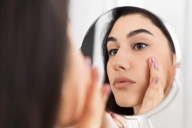 istock Girl Touching Face Looking In Mirror Indoor 1182434729