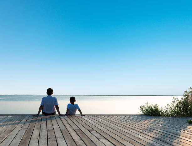 istock Father with his son enjoying lake view 1182435128