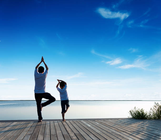 istock Father with his son doing yoga by the lake 1182436250