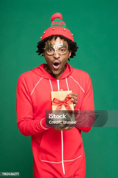 Funny Christmas Portrait Of Surprised Young Man Holding Present Stock Photo - Download Image Now