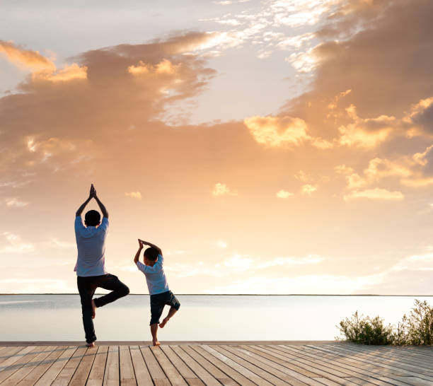 istock Father with his son doing yoga by the lake 1182436378
