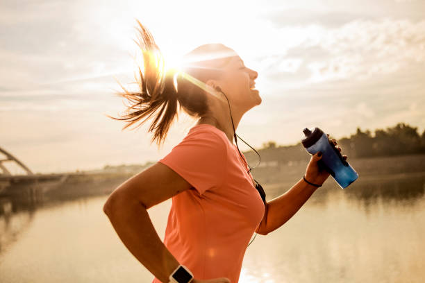 Young woman running against morning sun Young woman running headphones photos stock pictures, royalty-free photos & images