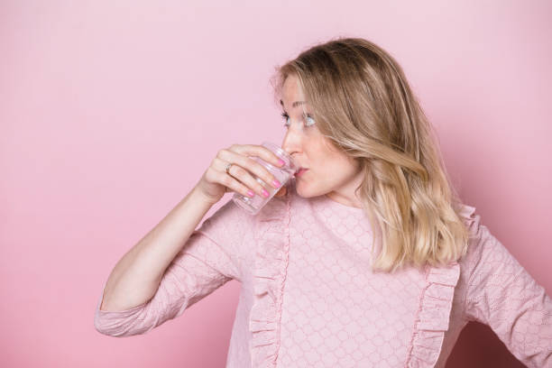 pregnant woman drinks water studio shot on pink background - dress human pregnancy young women women imagens e fotografias de stock