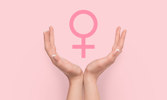 Women's power, feminism concept. Woman hands holding female gender sign on pink background.