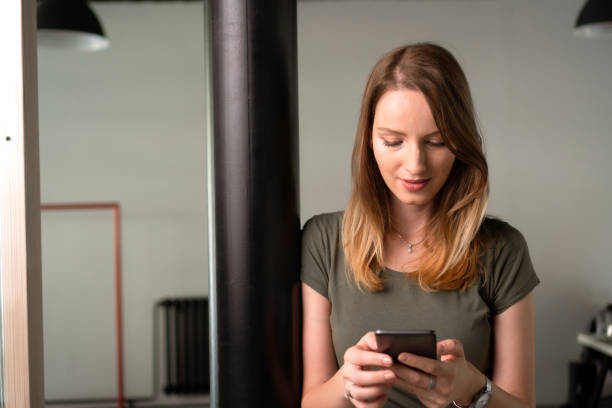 istock Sending messages - young woman holding mobile phone 1182440175