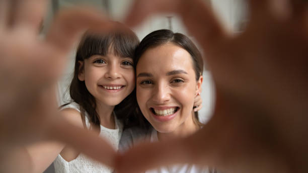 fermez-vous vers le haut de la famille heureuse de verticale de deux faisant le geste de coeur. - multi generation family adoption family human hand photos et images de collection