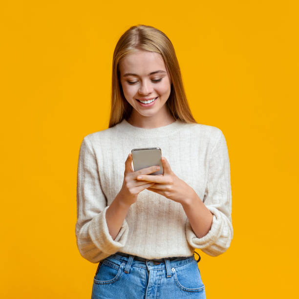istock Beautiful Girl Messaging On Smartphone Over Orange Background 1182440541