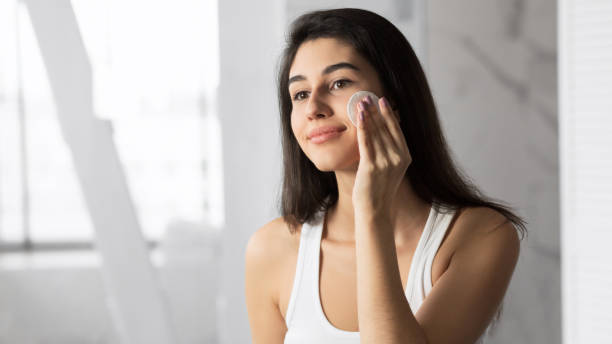 istock Young Woman Removing Makeup Using Cotton Pad In Bathroom 1182441439