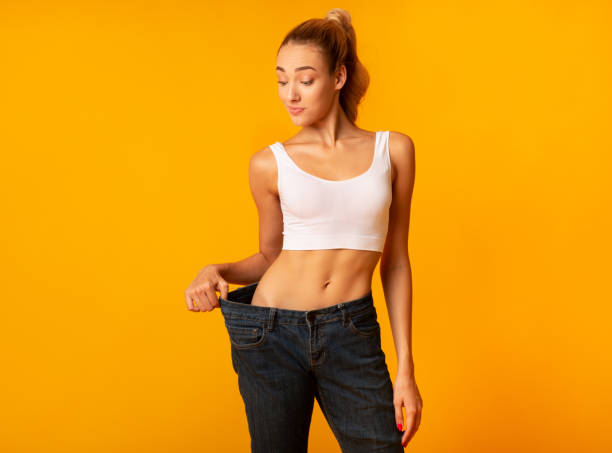 slim woman in oversize jeans posing standing in studio - perfect figure imagens e fotografias de stock