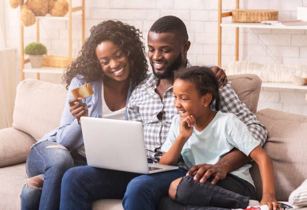 achats de famille d'afro-américain en ligne avec l'ordinateur portatif et la carte de crédit - internet e commerce credit card retail photos et images de collection