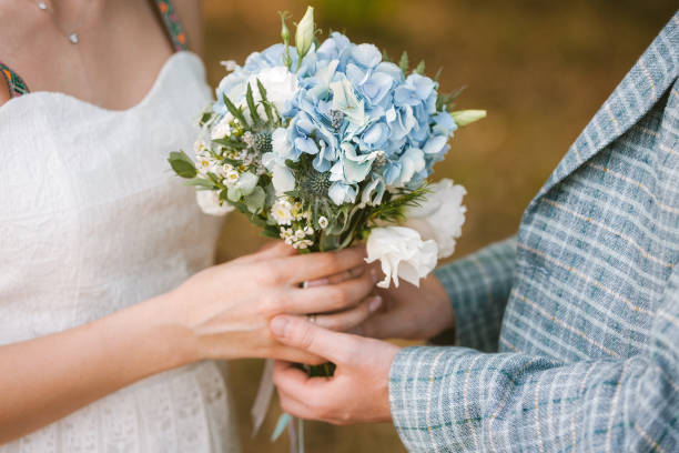 istock bride and groom holding wedding bouquet 1182447563