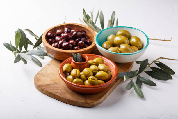 différents types d'olives vertes et noires dans des bols sur table blanche. - spanish olive photos et images de collection