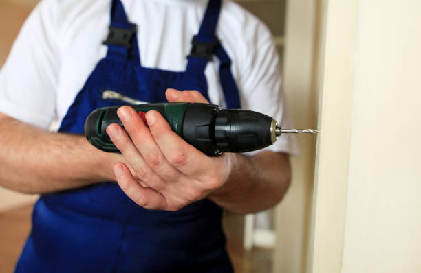 istock Construction worker and handyman works on renovation of apartment. Builder with electric drill drills nail hole into wooden wall door at construction site. Home renovation concept. Construction tool. 1182448656