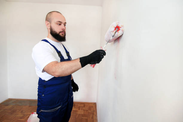 istock Construction worker doing finish renovation at apartment. Professional painter contractor using white paint roller brush painting of concrete wall room on construction site. Home renovation concept. 1182449134
