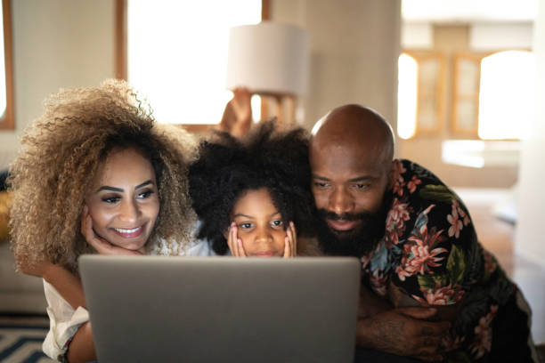счастливая семья смотрит фильм на ноутбуке - lying down women laptop freedom стоковые фото и изображения